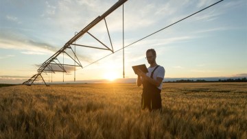Sistem de irigatii monitorizat de un barbat cu ajutorul tabletei intr-un camp cultivat